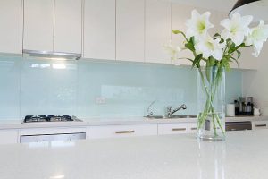 Flowers on white kitchen bench with splashback
